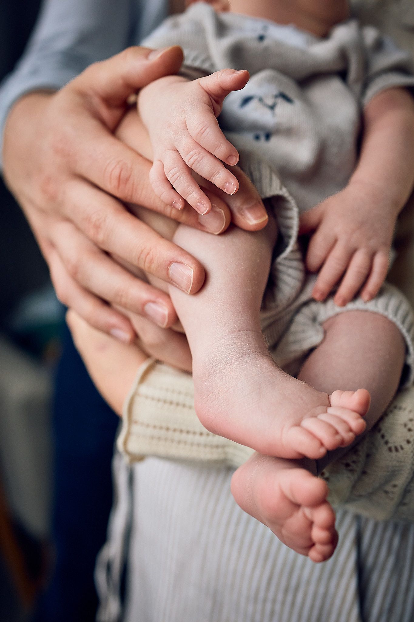 Series of close-up shots showing tiny baby feet being held by gentle hands.