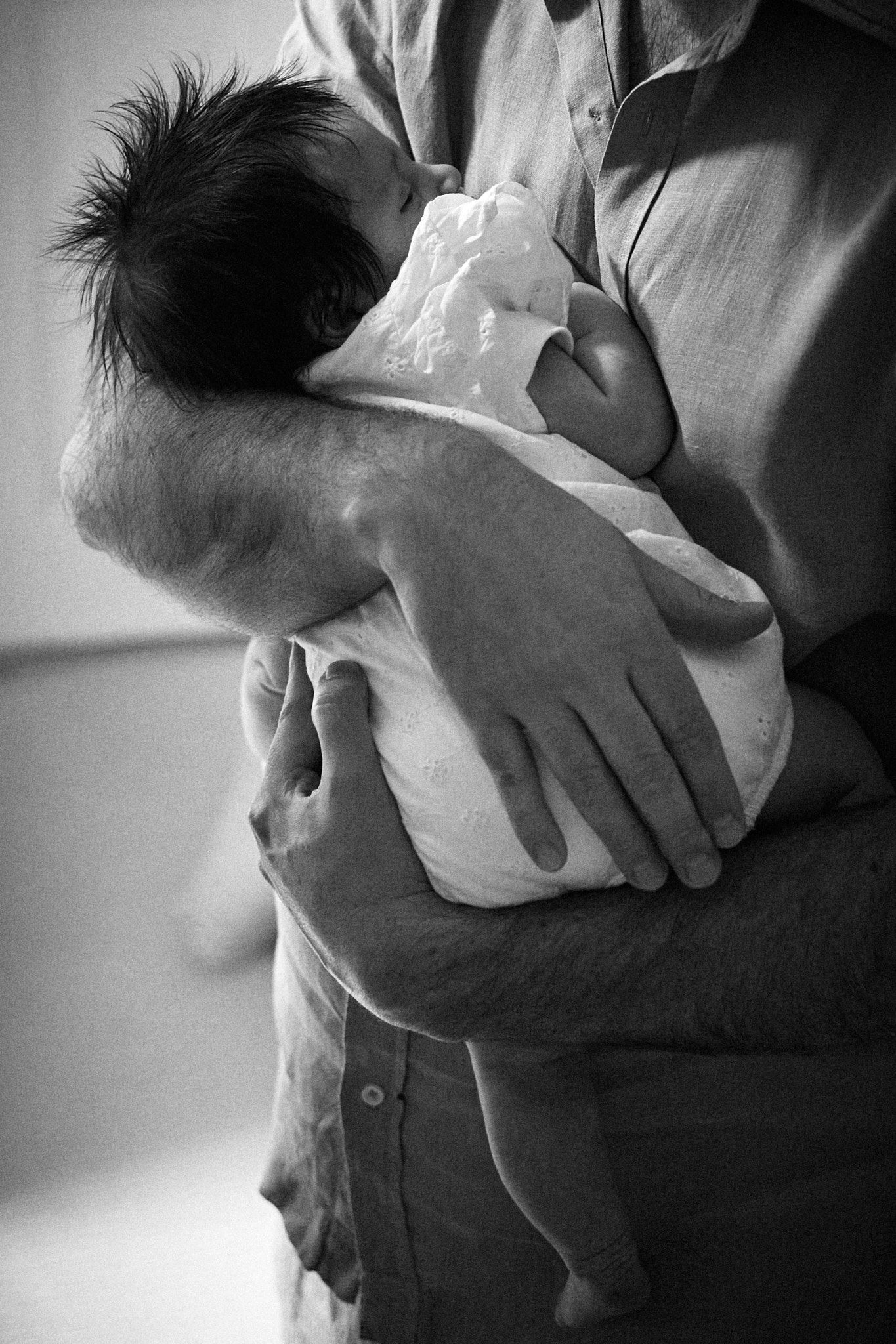 Black and white sequence showing gentle hands holding and supporting a small baby.