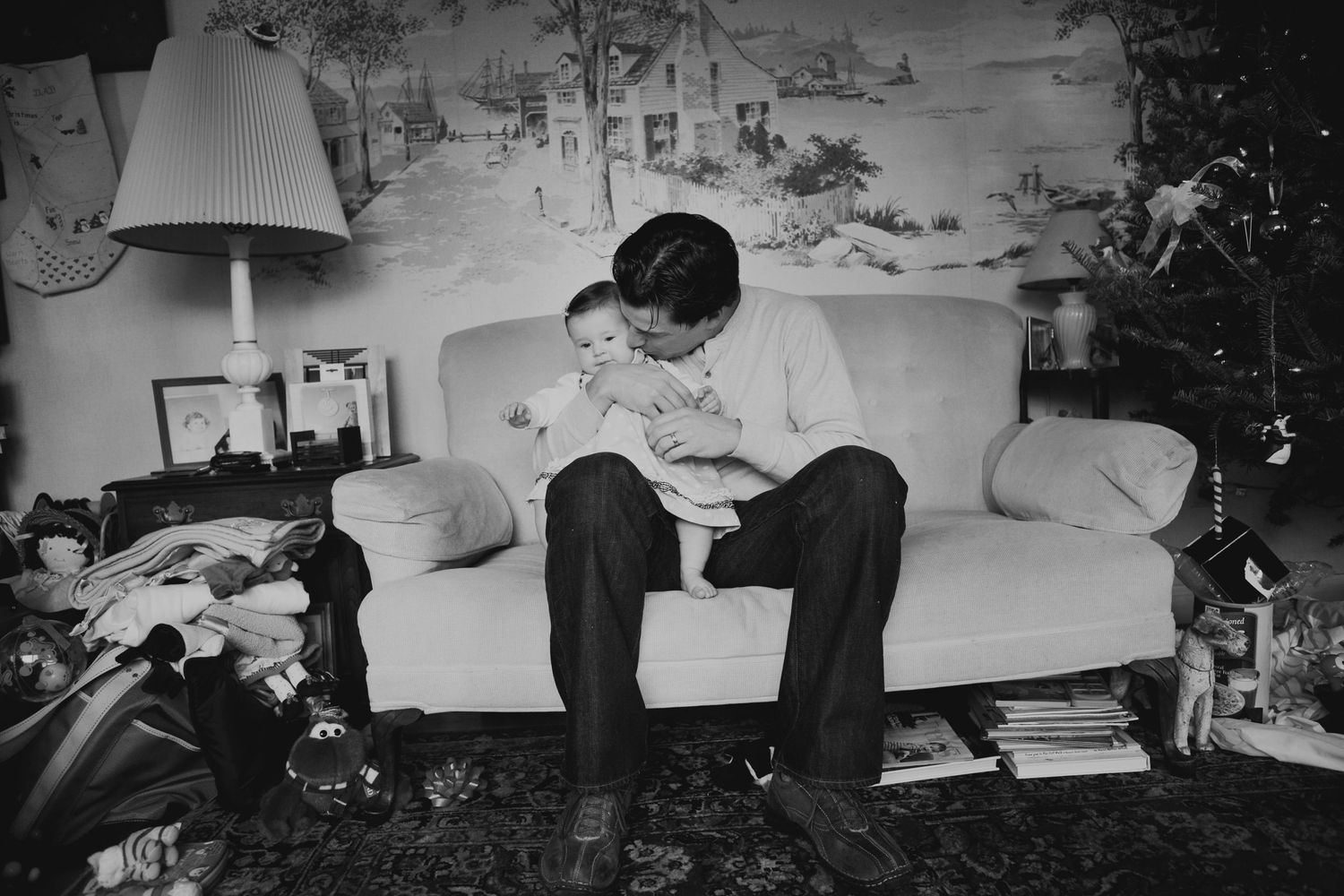 Black and white photograph showing quiet moment on couch with Christmas tree in background.