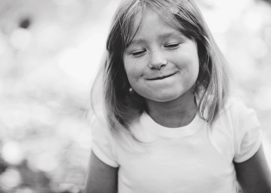 Young child smiling sweetly in black and white portrait.