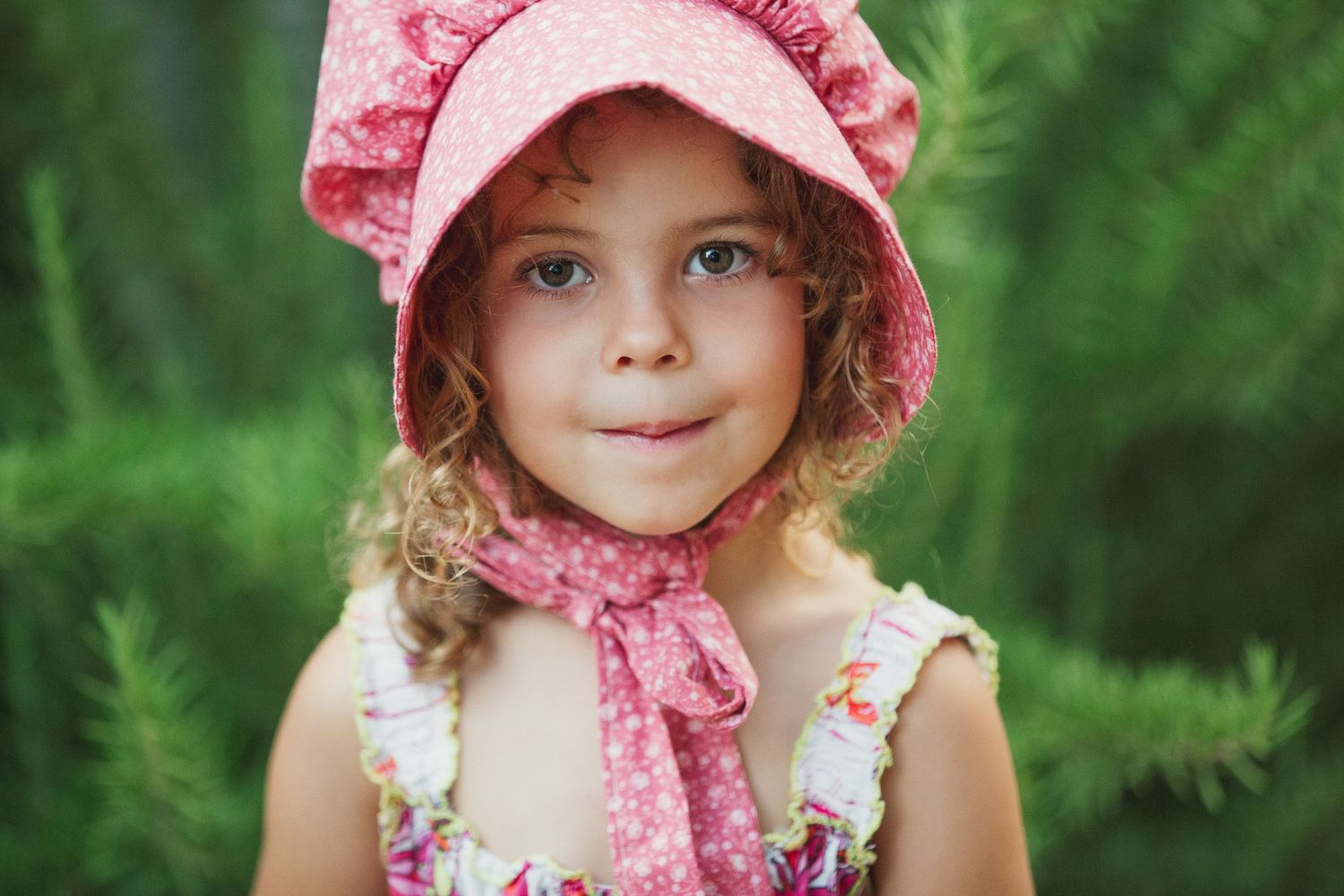 A portrait in a pink bonnet and floral dress against a green background.