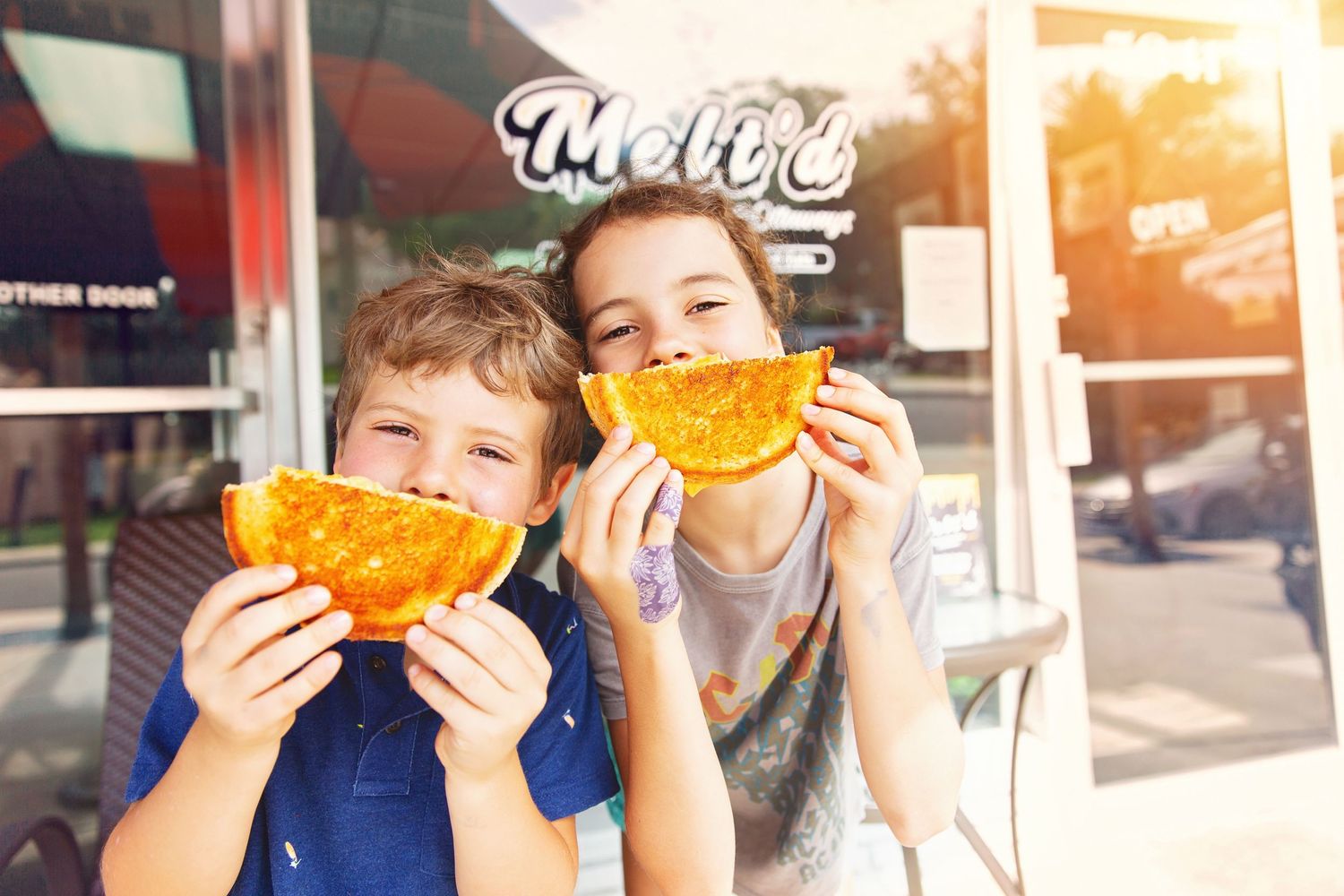 Two people enjoying orange-shaped snacks outside a storefront.