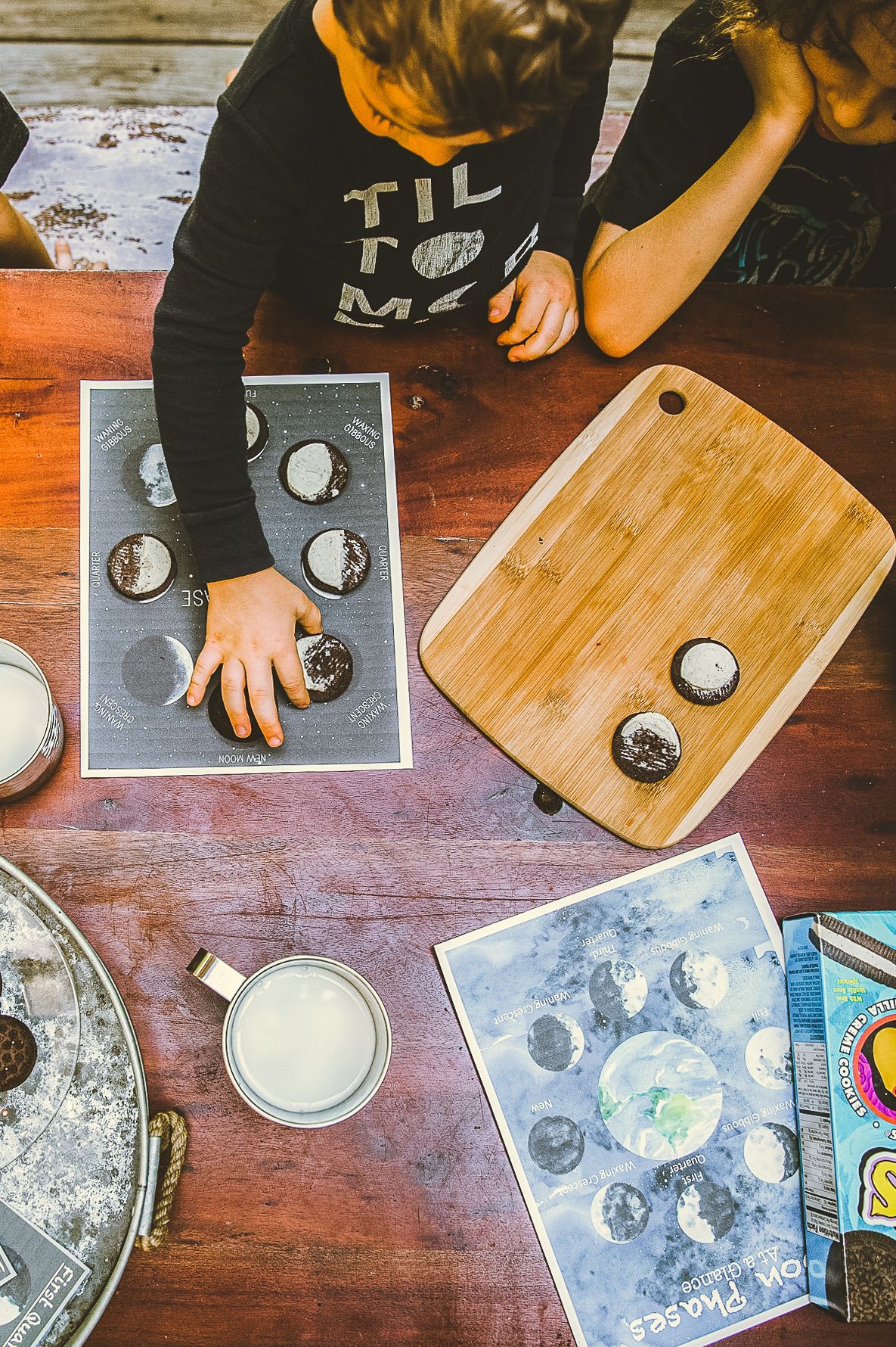 Overhead view of moon phase activity with cookies and educational materials on wooden table.