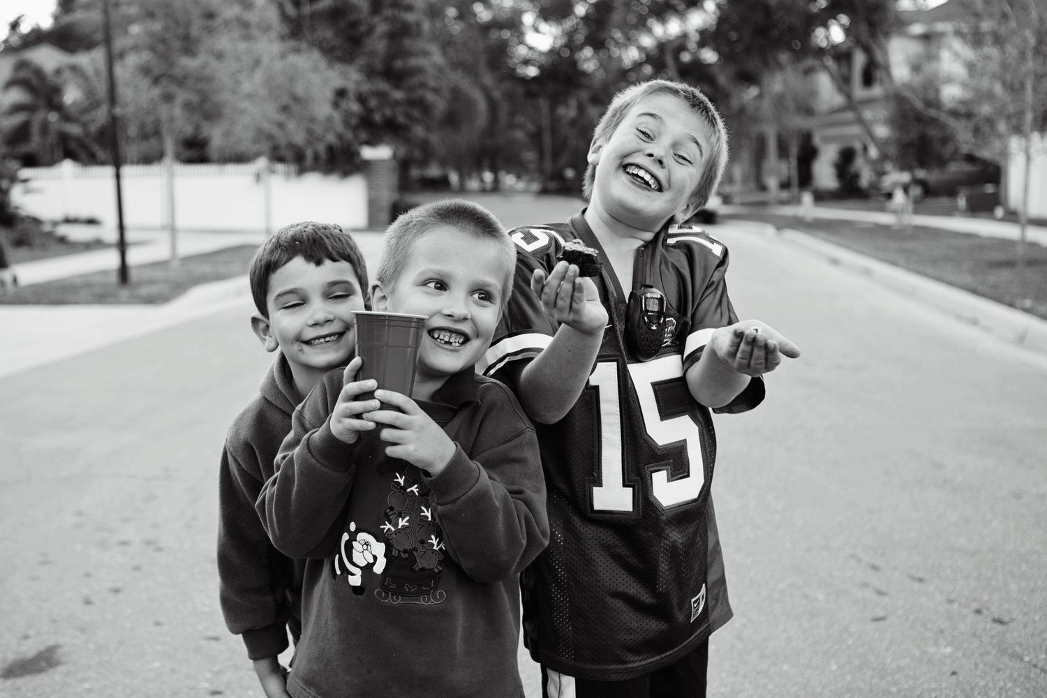 Three children playing and laughing together outdoors in black and white.