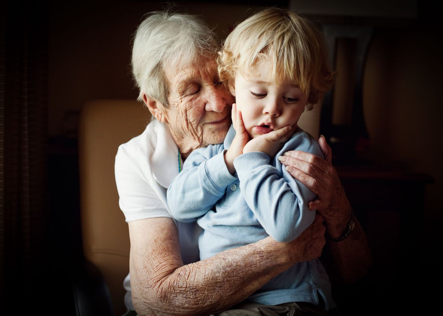 An elderly person shares a joyful moment with a small child in a warm embrace.