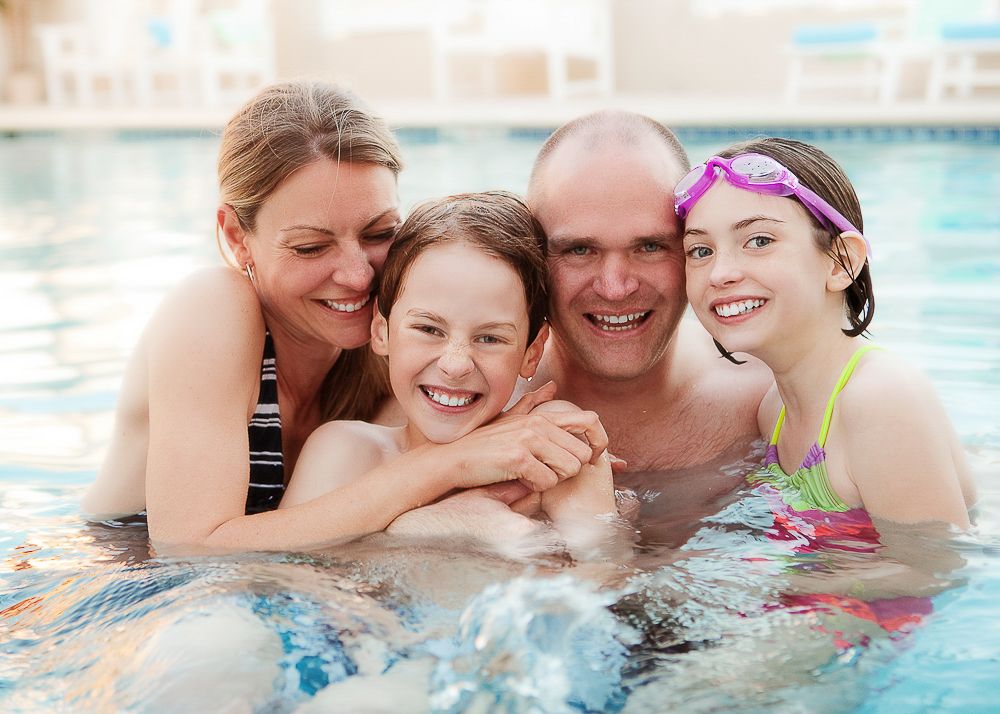 A happy family enjoying time together in a swimming pool on a sunny day.