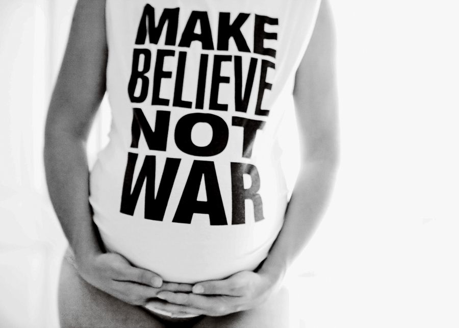 Close-up of a white t-shirt with 'MAKE BELIEVE NOT WAR' text.