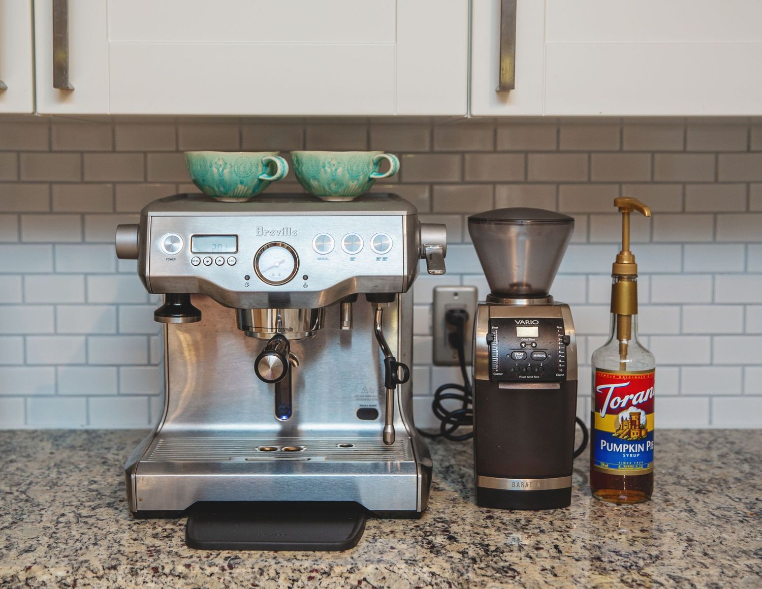 Professional coffee station setup with espresso machine, grinder and coffee accessories on granite counter.