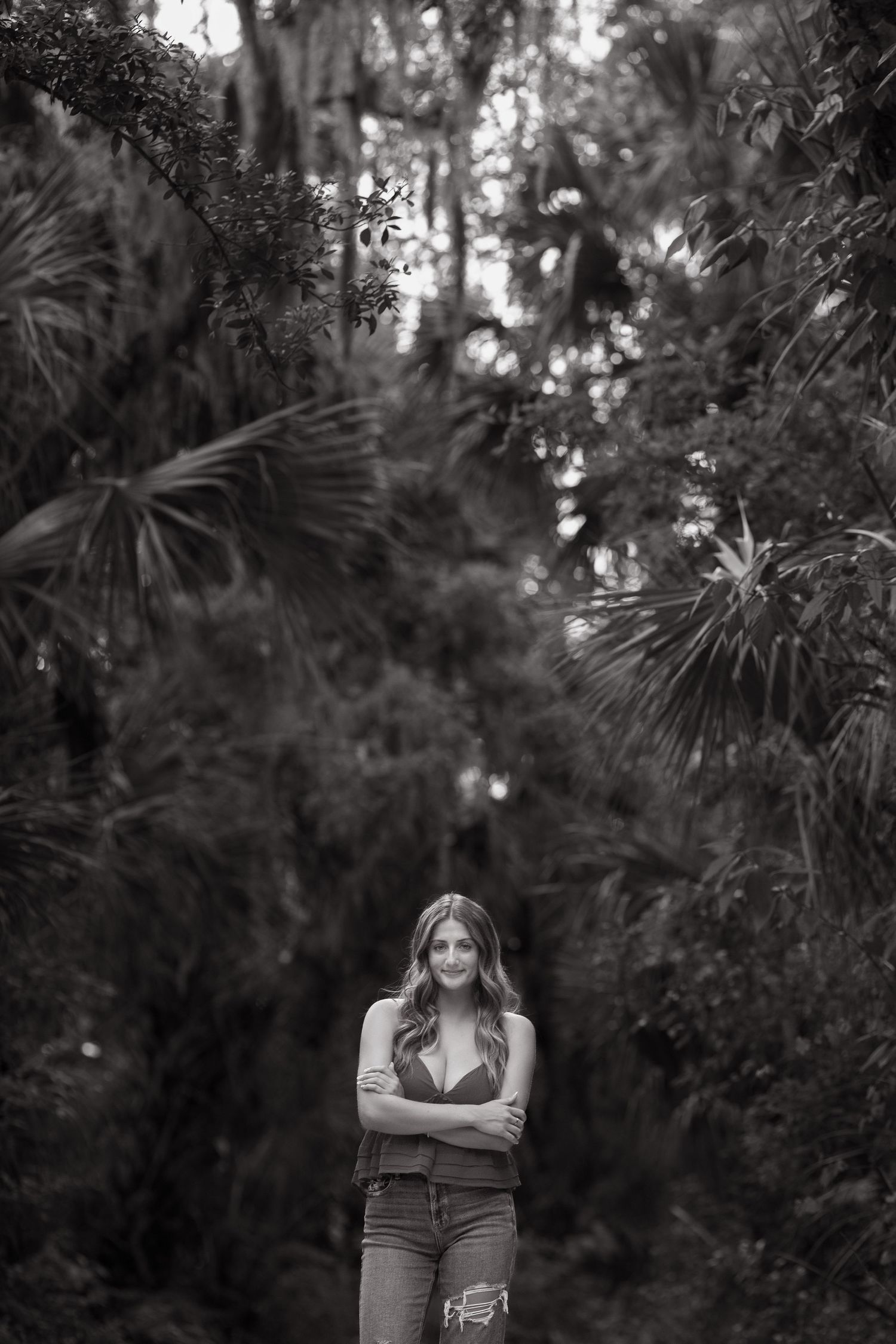Artistic black and white portrait in a lush tropical forest setting.