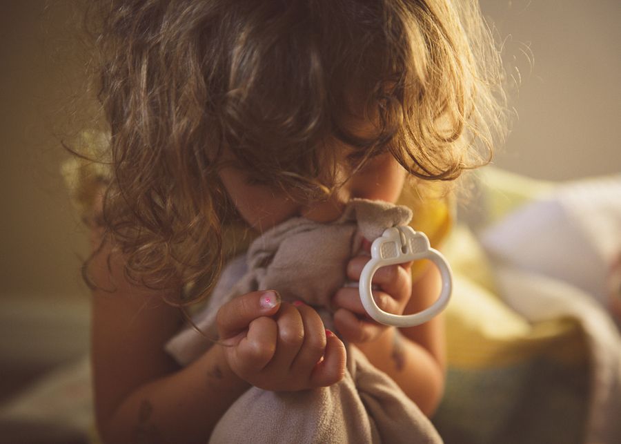 Child drinking from white teacup in warm sunlit room.