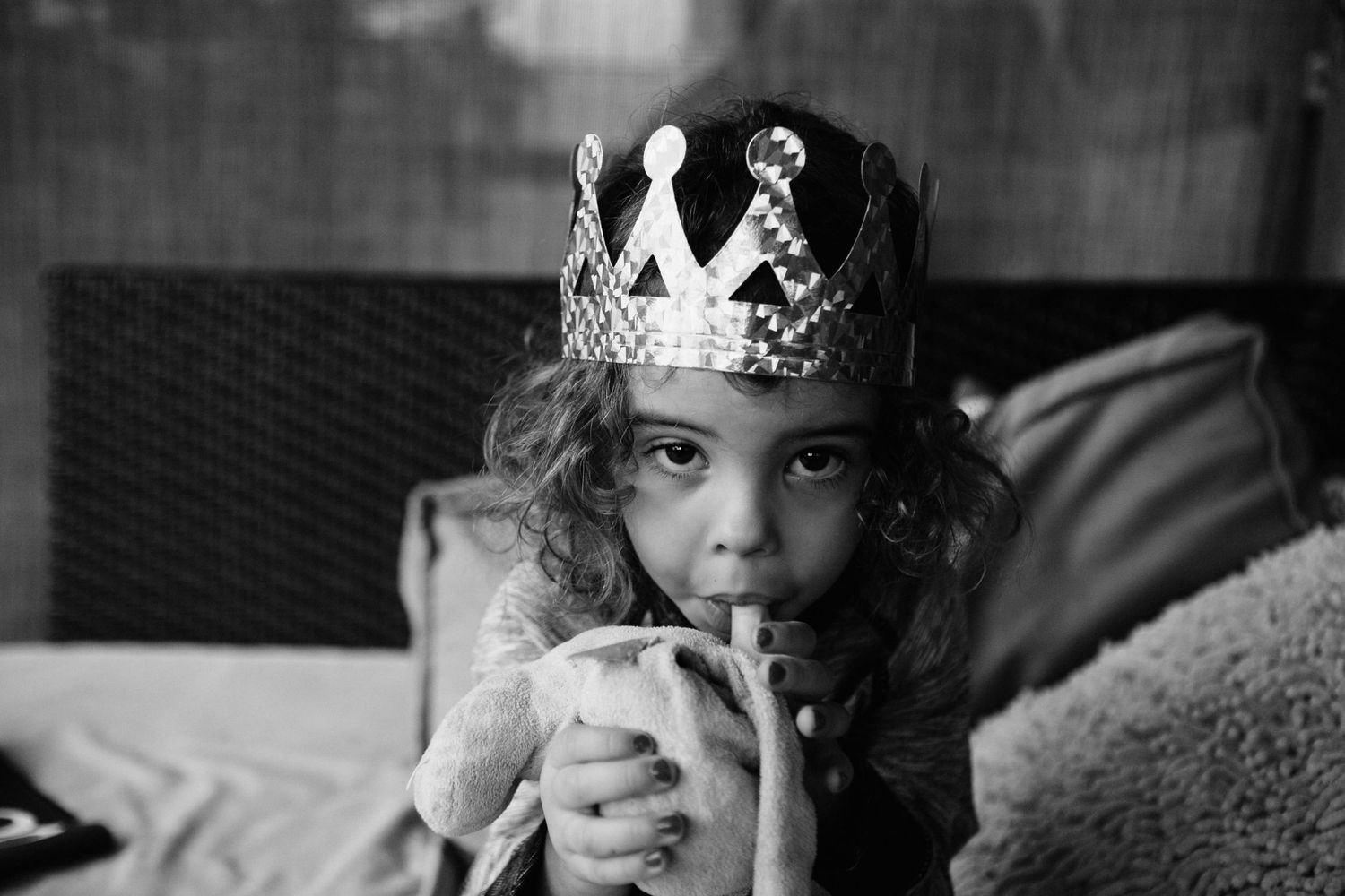 Black and white image of figure wearing crown while drinking from cup.