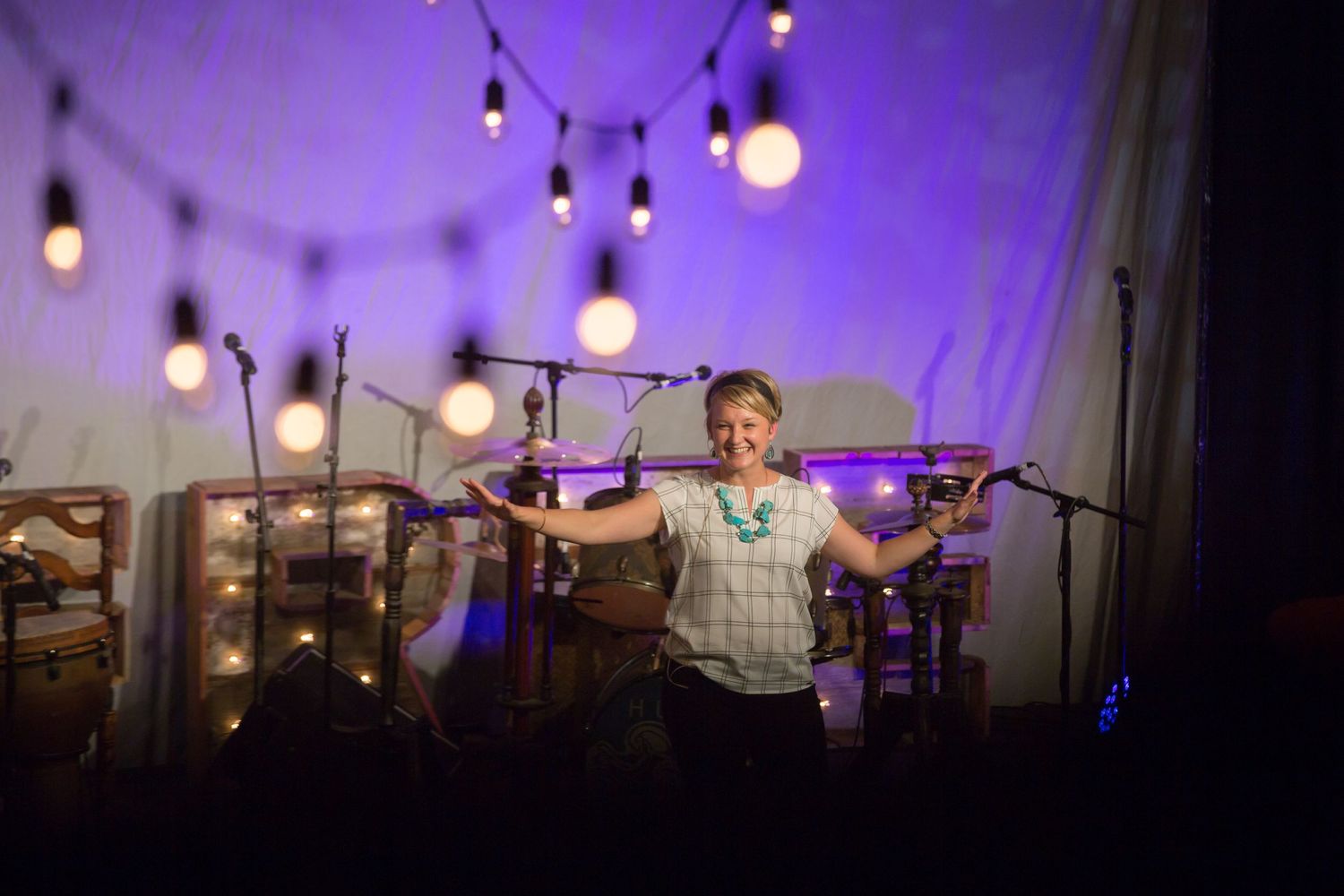 Performer on stage with string lights and purple lighting effects.
