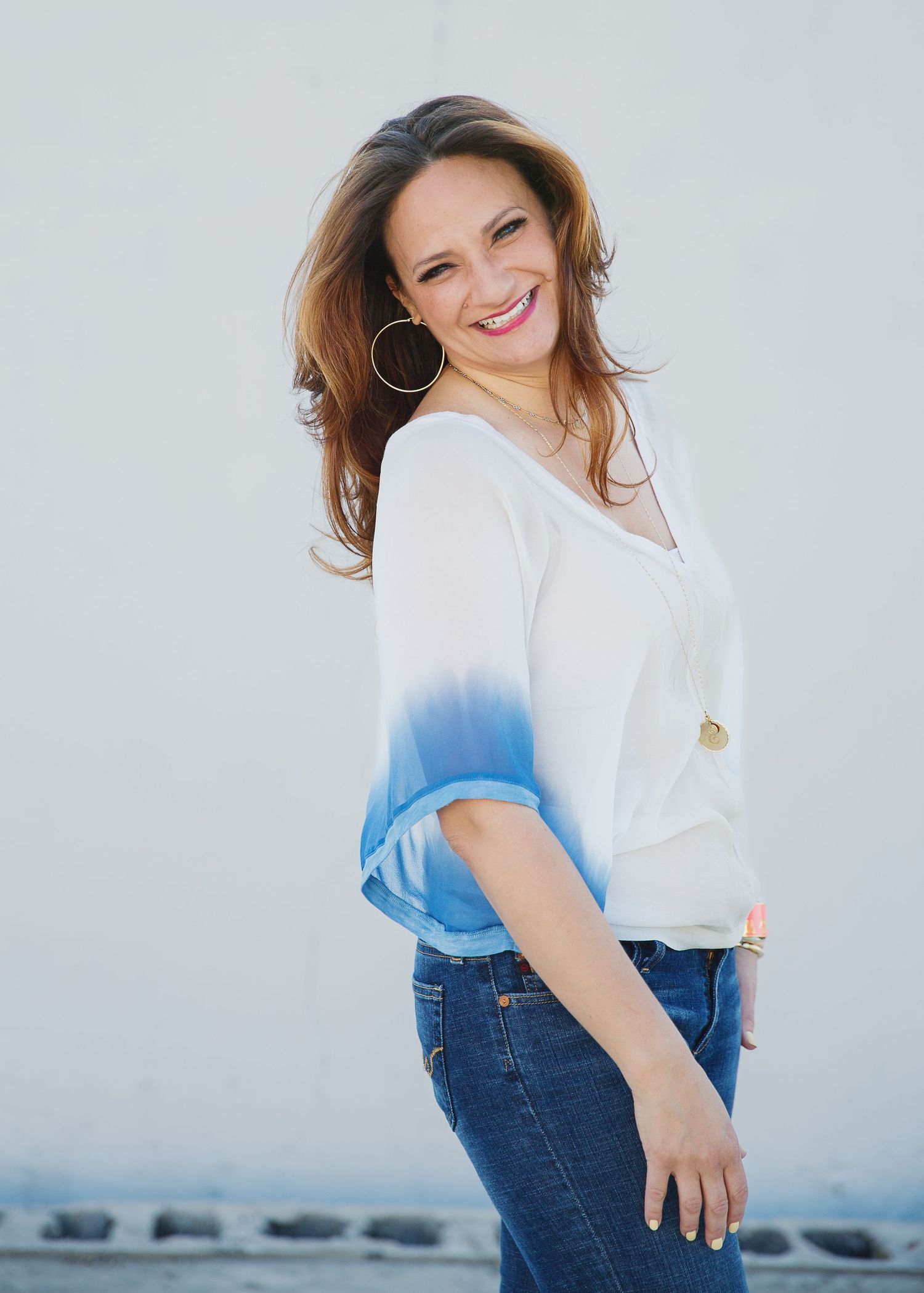 Casual portrait in dip-dyed white and blue top with jeans against light background.