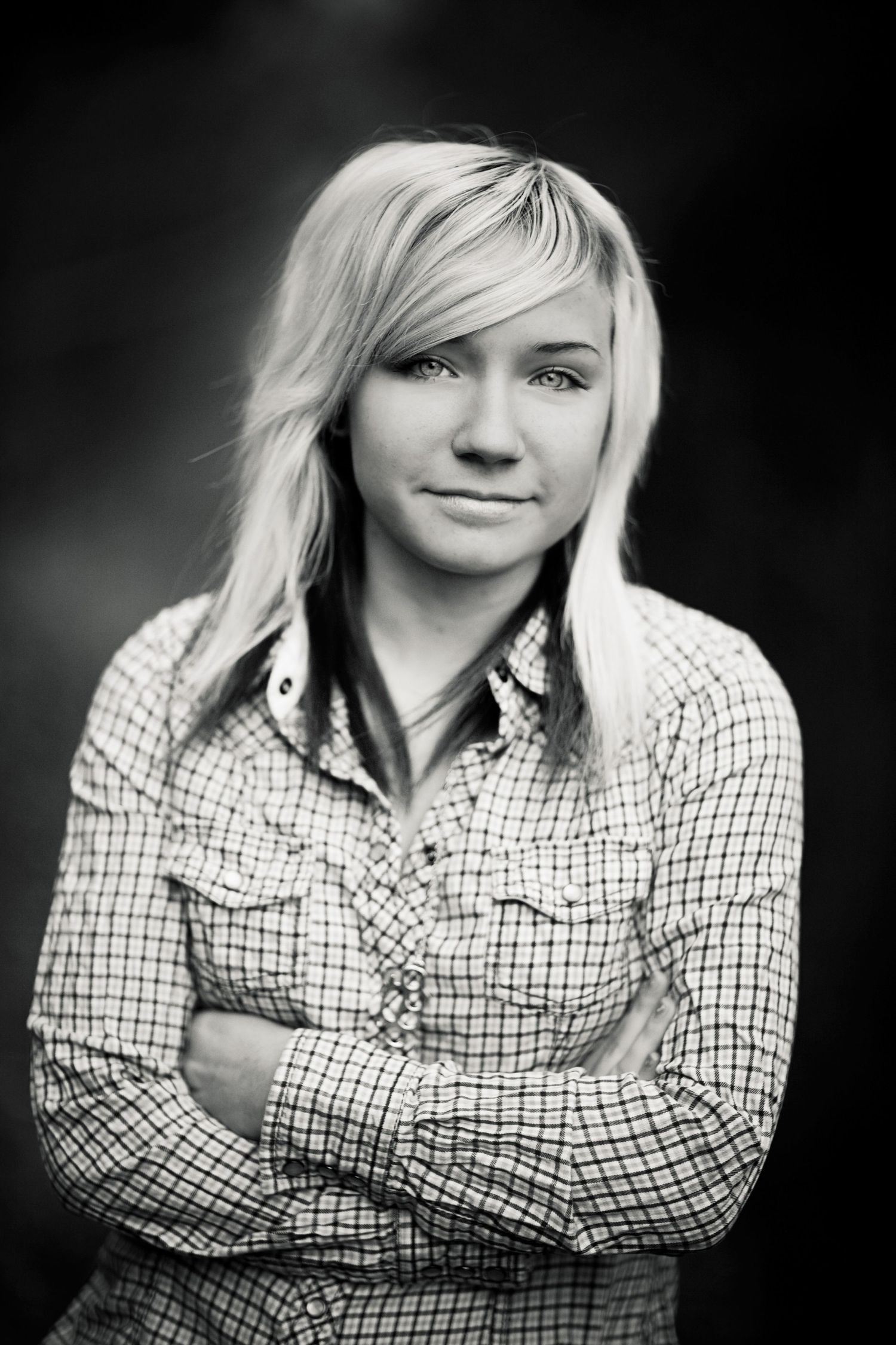 Black and white portrait in plaid button-up shirt with crossed arms.