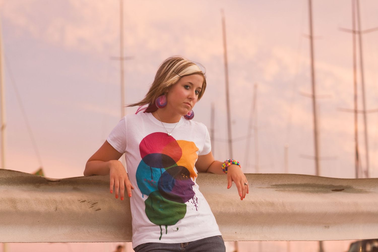 Portrait wearing a white t-shirt with colorful graphic design against sunset marina background.