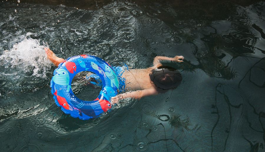 Swimmer floating in dark water with a bright blue and red inflatable ring tube.