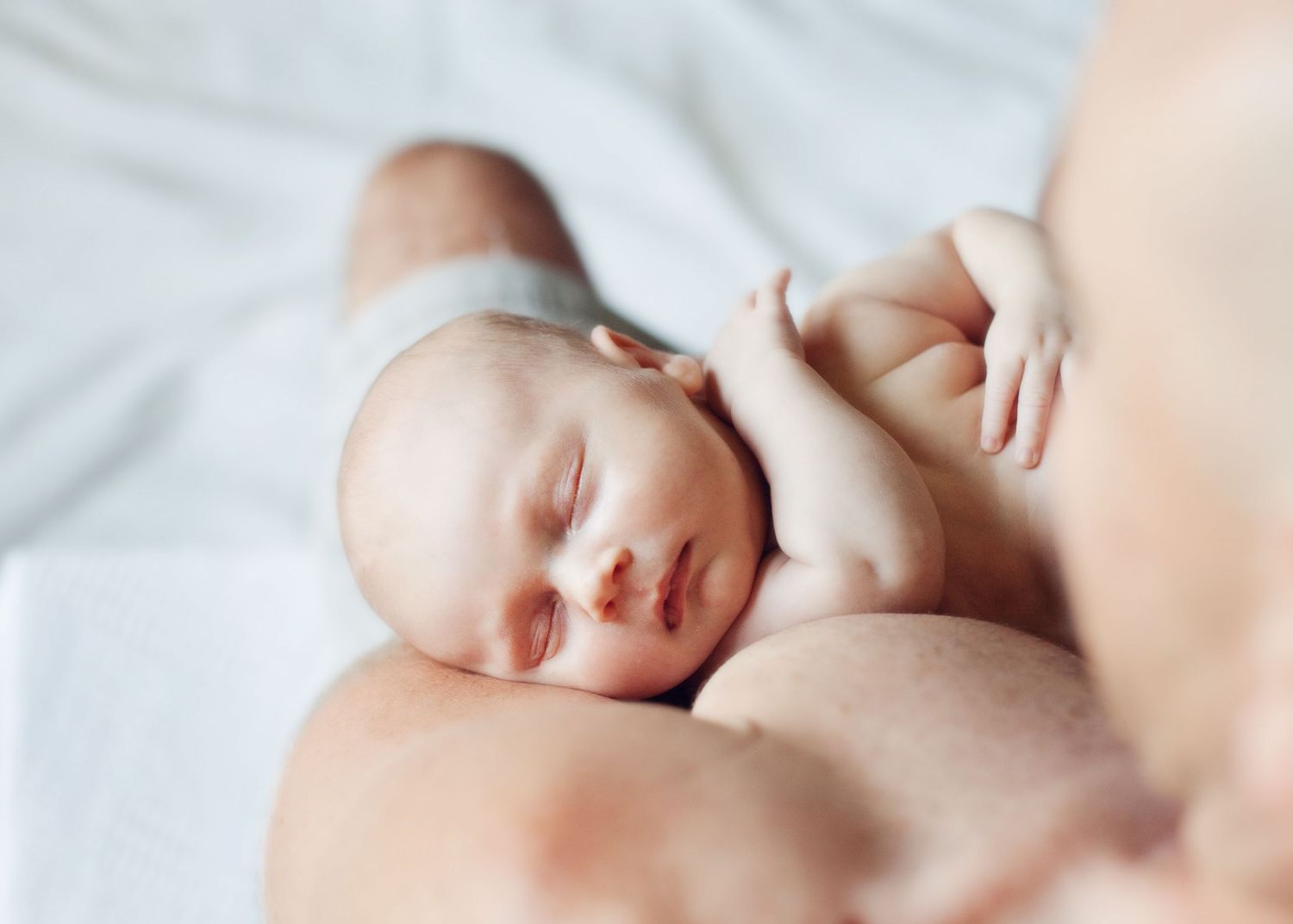 Peaceful sleeping newborn baby resting on soft white bedding.