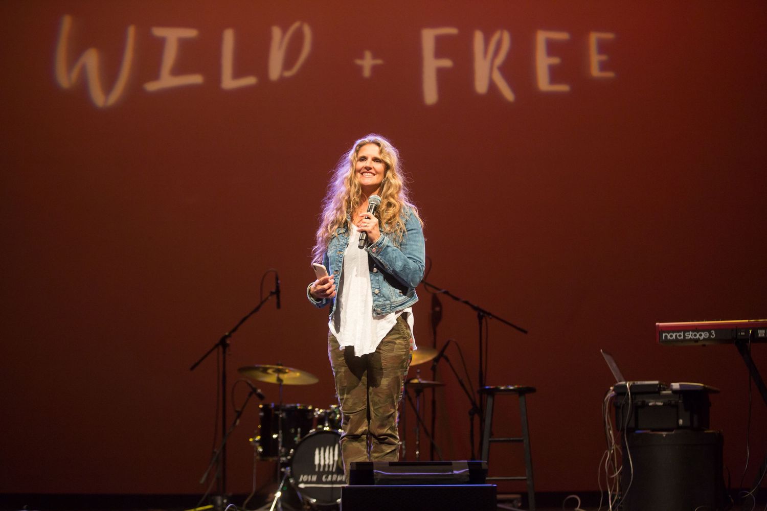 A performer on stage with 'Wild + Free' text projected behind them.