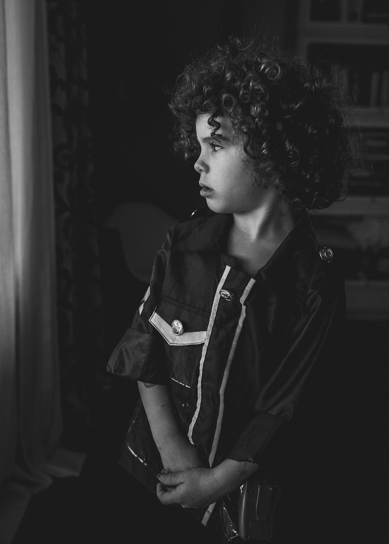 A moody black and white portrait showing curly hair and leather jacket in profile.