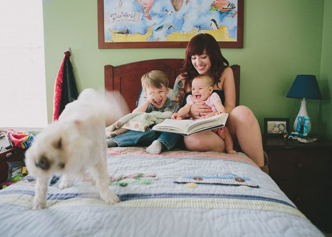 Reading time on bed with white dog as companion and colorful wall art in background.