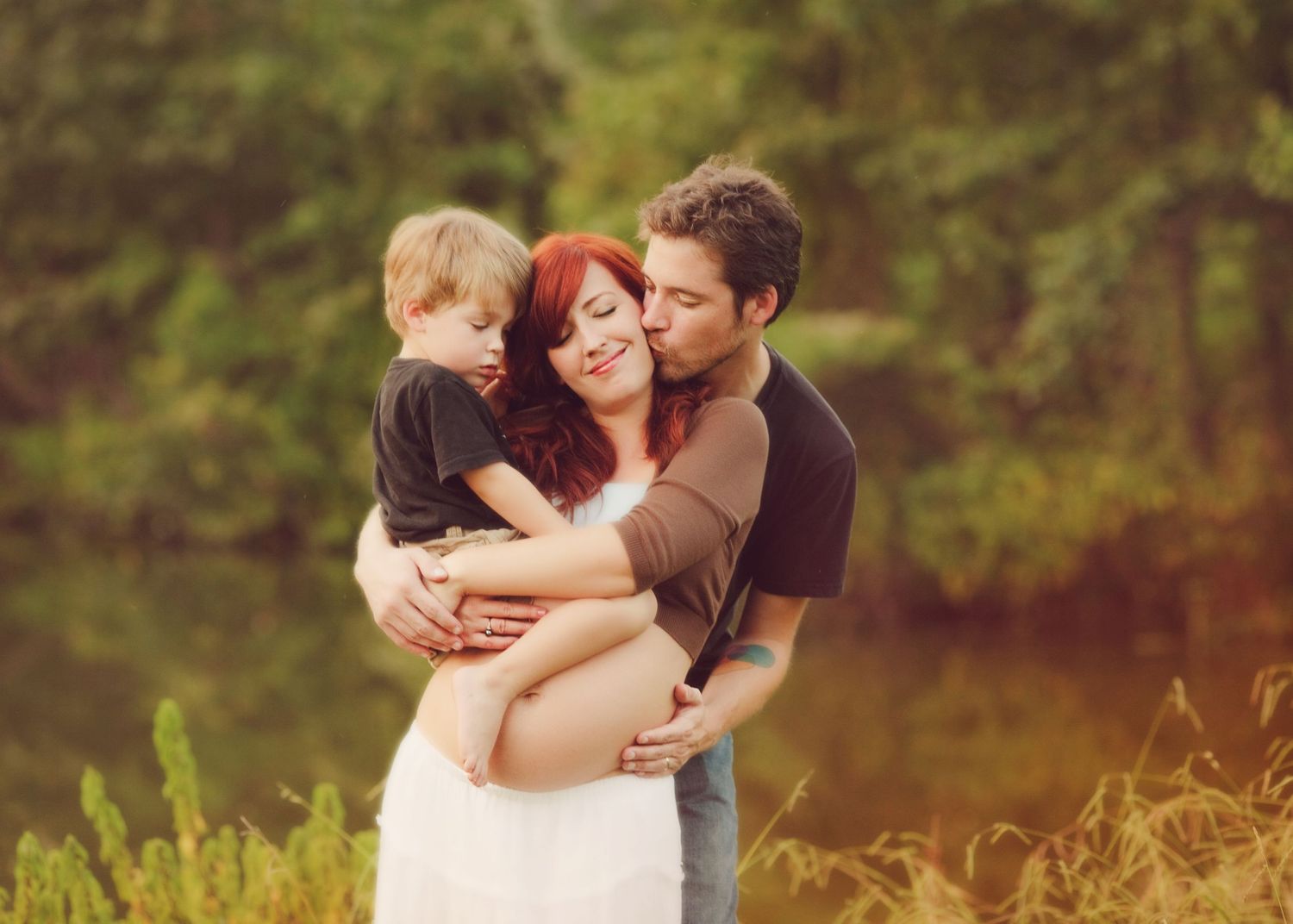 Family sharing an intimate embrace outdoors in warm sunset lighting.