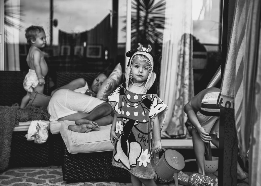 Vintage black and white photo of a laughing child in costume playing at home.