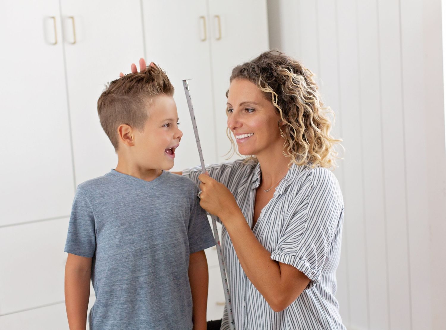 Two people sharing a candid laughing moment in front of white closet doors.