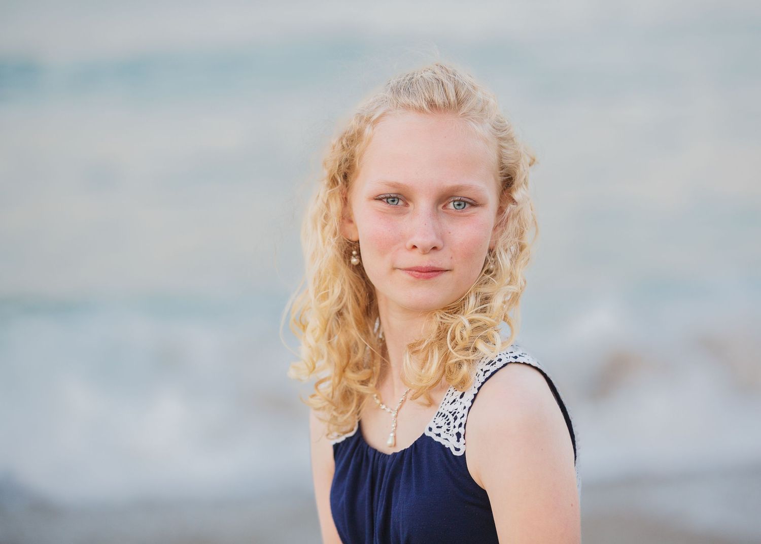 Beachside portrait with soft lighting and ocean waves in background.