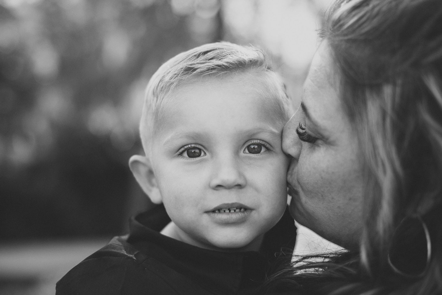 A tender black and white portrait capturing an intimate family moment between parent and child.