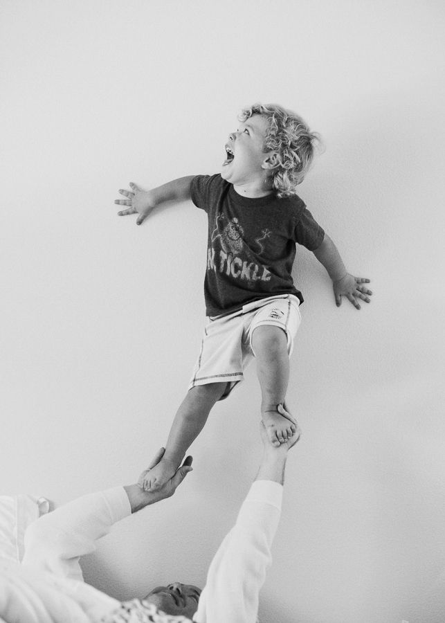 Child being lifted in the air against white background.