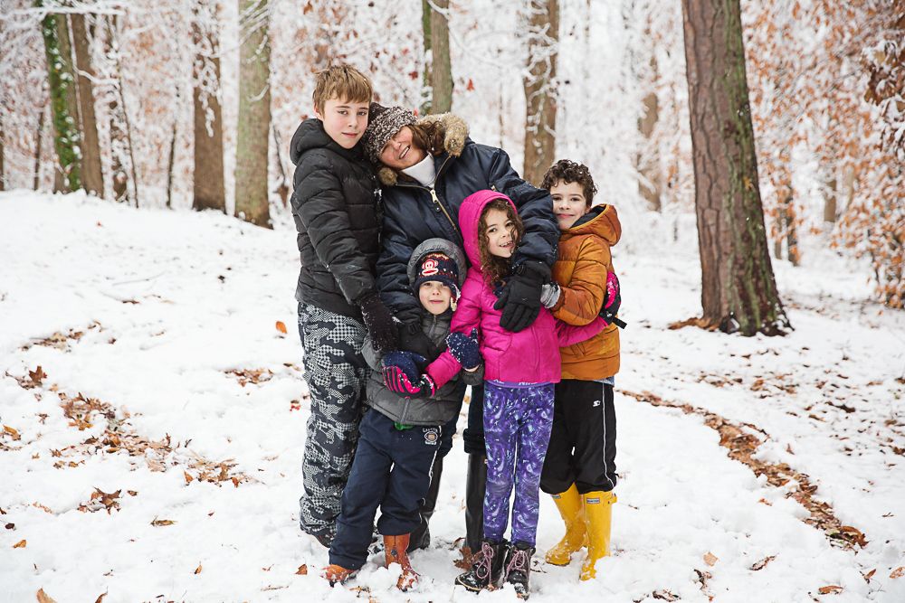 Group of people huddled together in snowy winter forest setting.