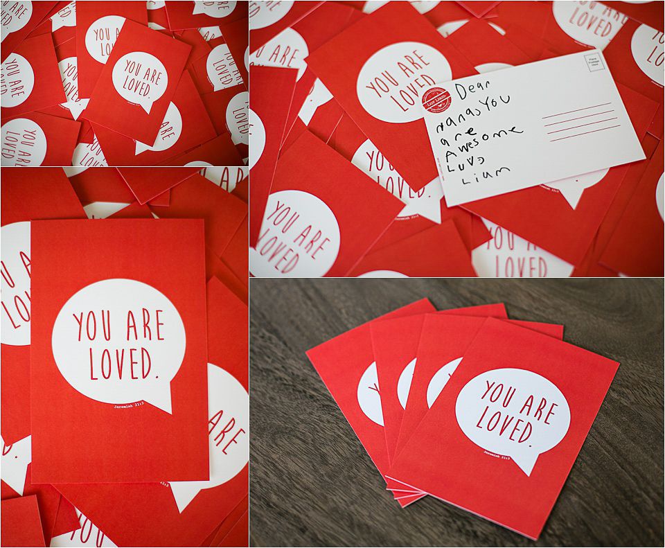 Red greeting cards with 'You Are Loved' message in white speech bubbles spread across a dark surface.