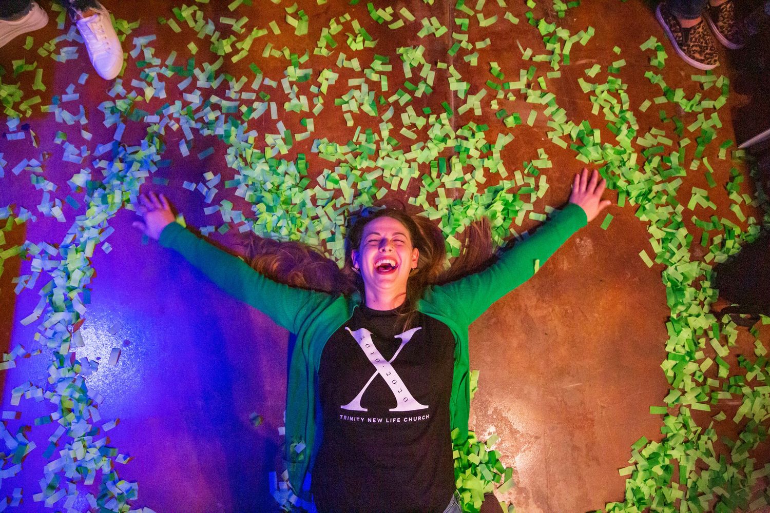 Person celebrating at night with colorful lights and leaf projections creating a magical atmosphere.