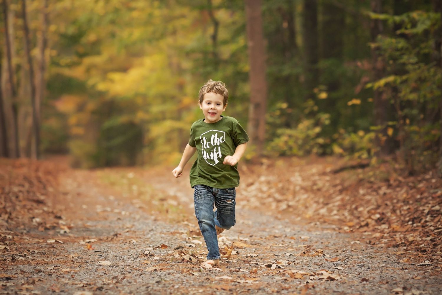 Someone running down an autumn path covered in fallen leaves.