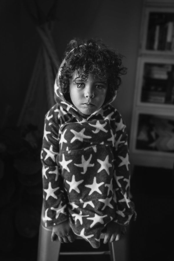 Black and white portrait of a child wearing a cozy star-patterned hoodie sweater.
