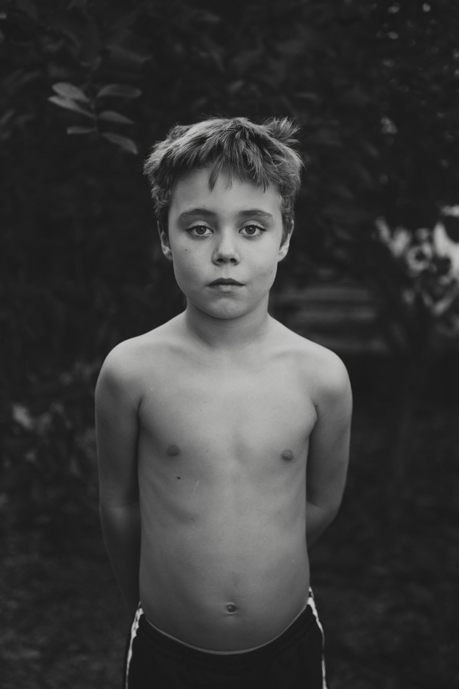 Black and white portrait against dark foliage background.