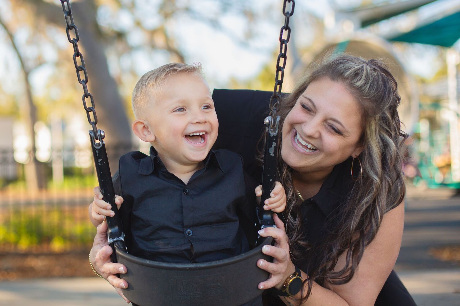 A joyful moment captured at a playground as parent and child share laughter while swinging together.