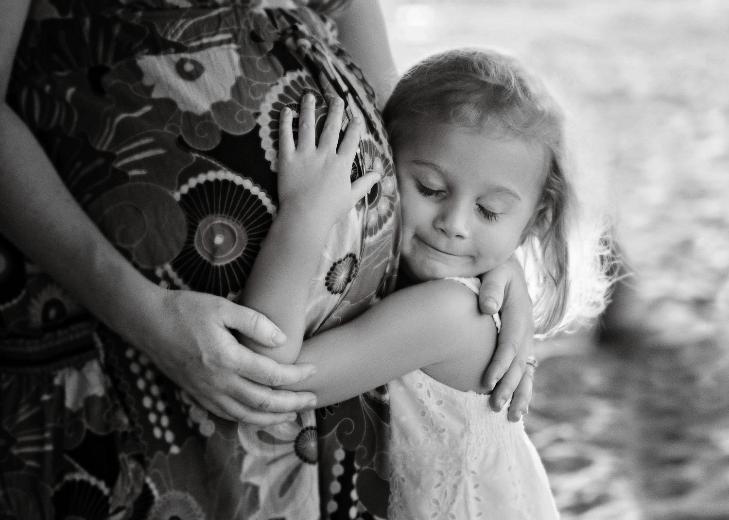 A tender moment showing someone hugging a pregnant belly in black and white.