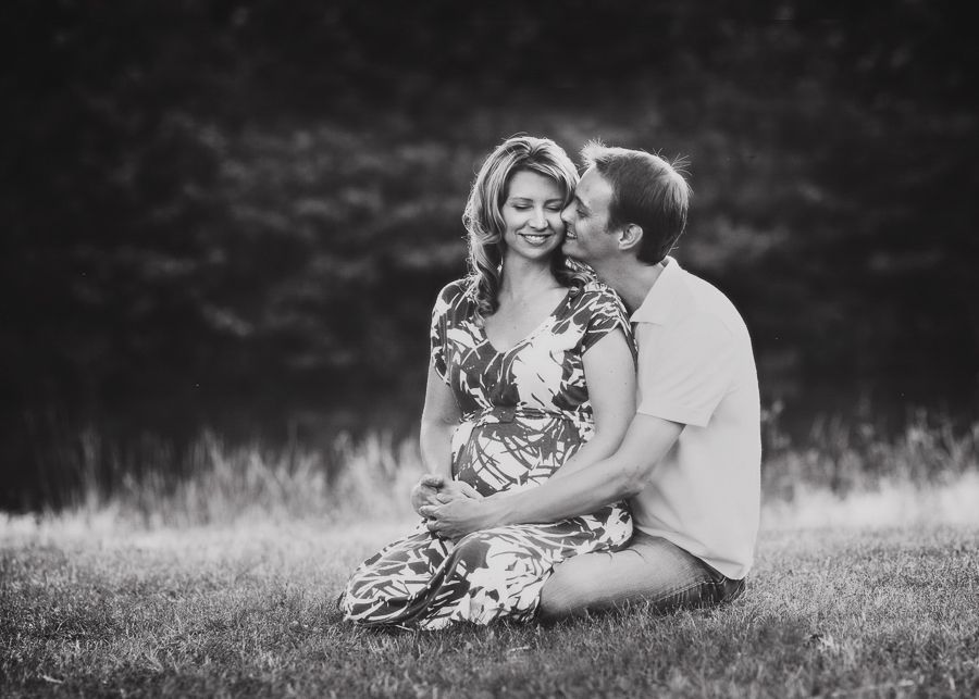 Romantic couple sharing intimate moment while sitting in grassy field.