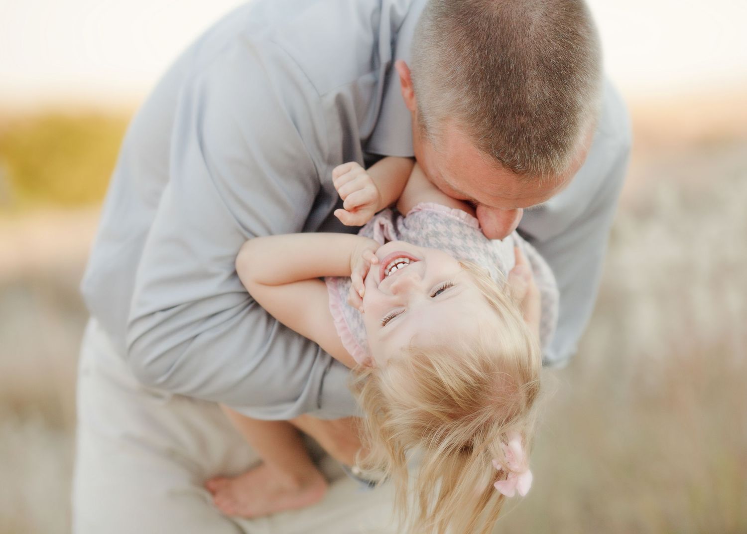 A touching moment of parent and child playing together against a bright outdoor backdrop.
