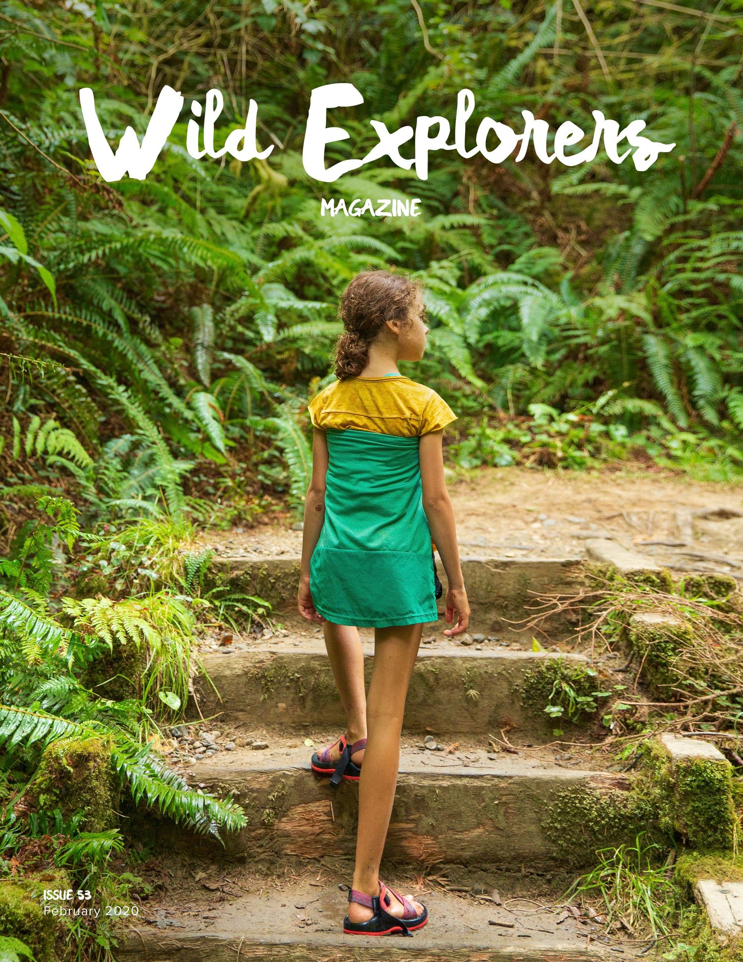 Magazine cover showing explorer in green dress standing on stone steps in lush forest.