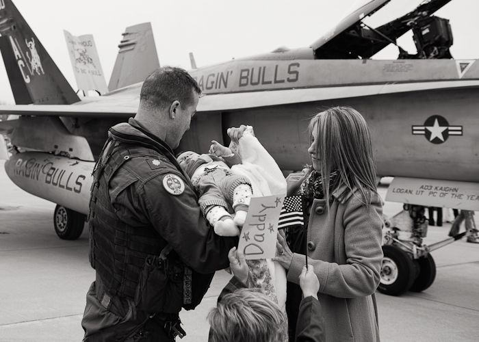 Military personnel in flight gear interacting with civilians in front of an aircraft on display.
