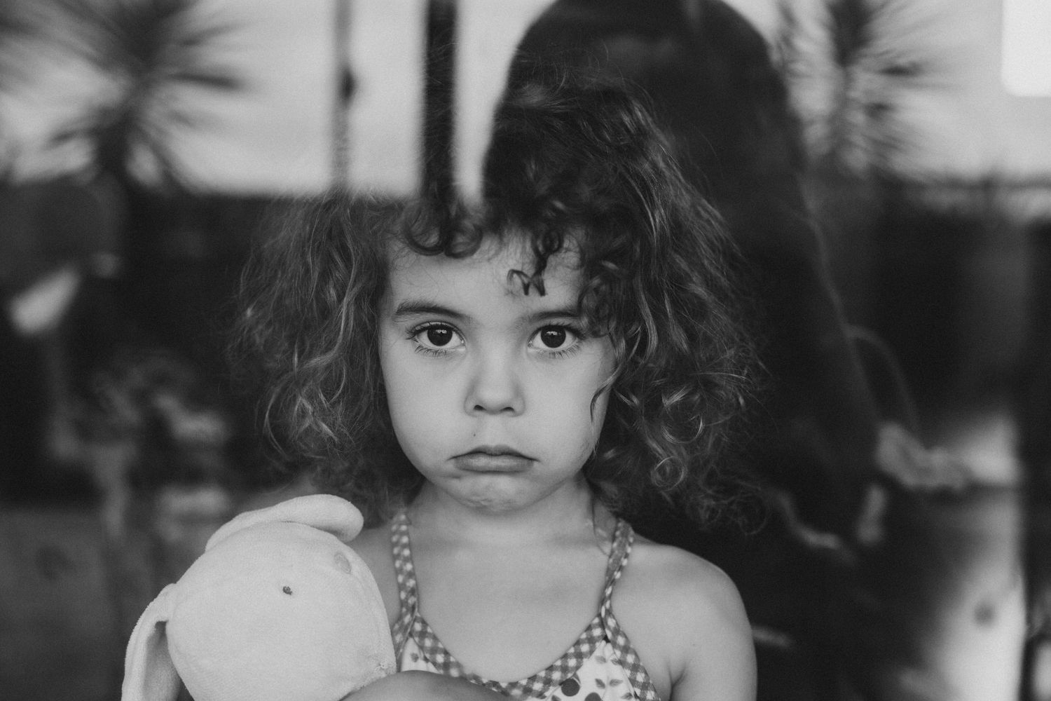 A vintage-style black and white portrait of a small child wearing a patterned dress.