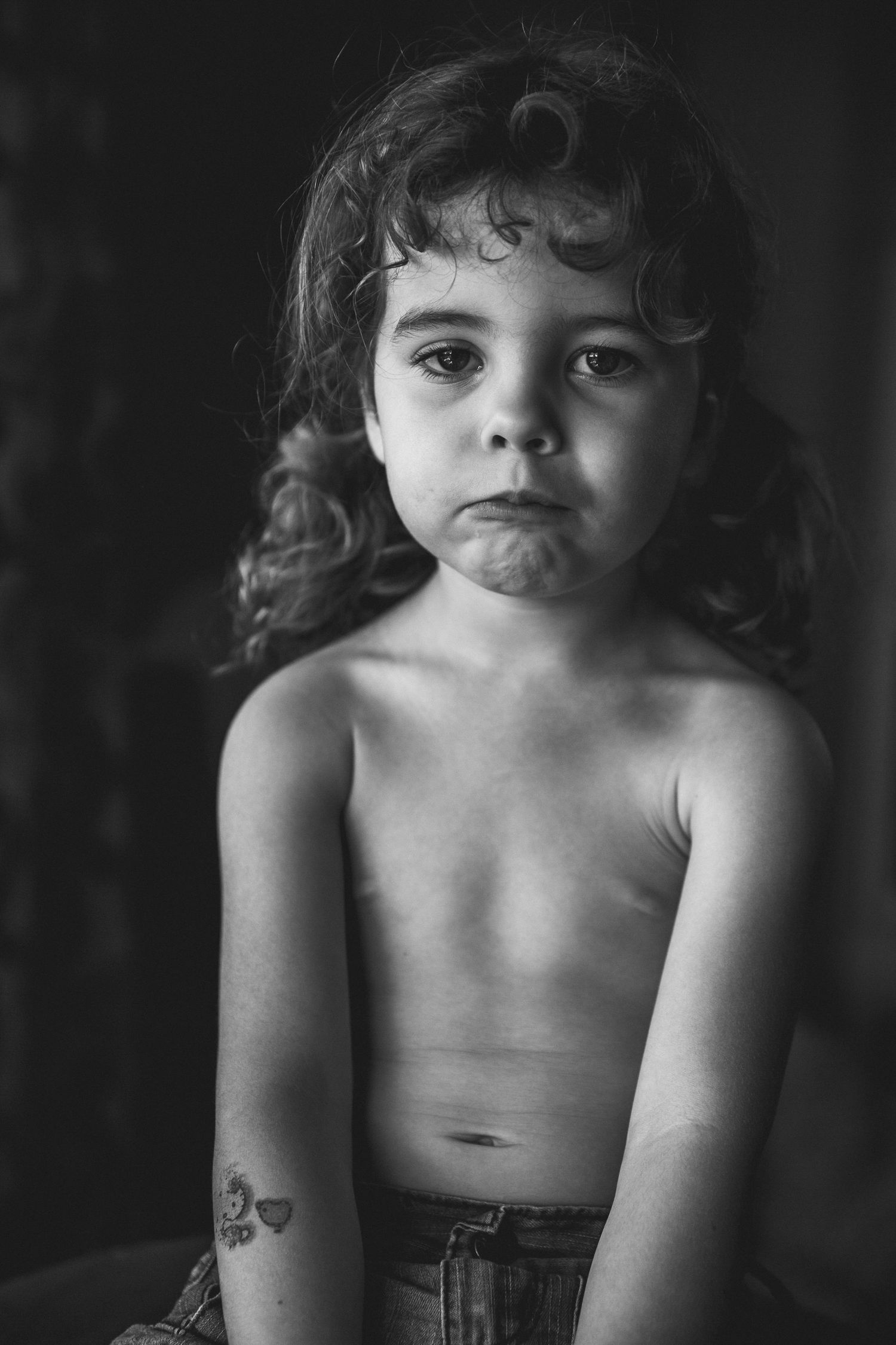 Moody black and white portrait showing curly hair and innocent expression.