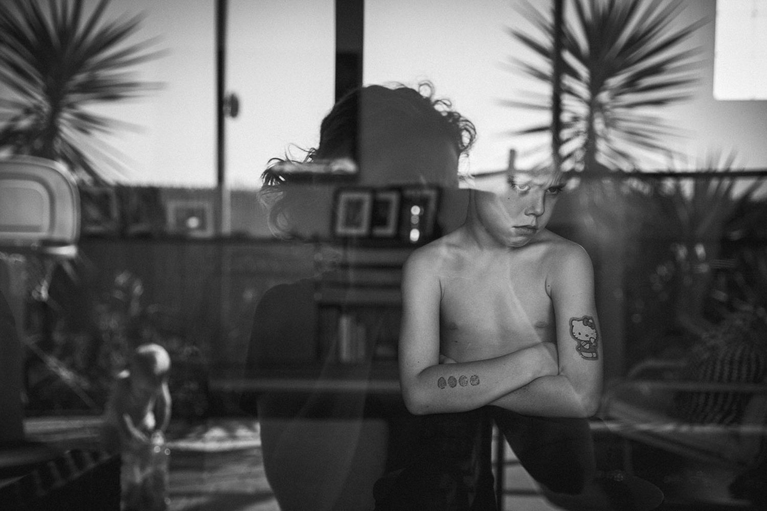 A silhouetted figure against palm trees in soft focus through window glass.
