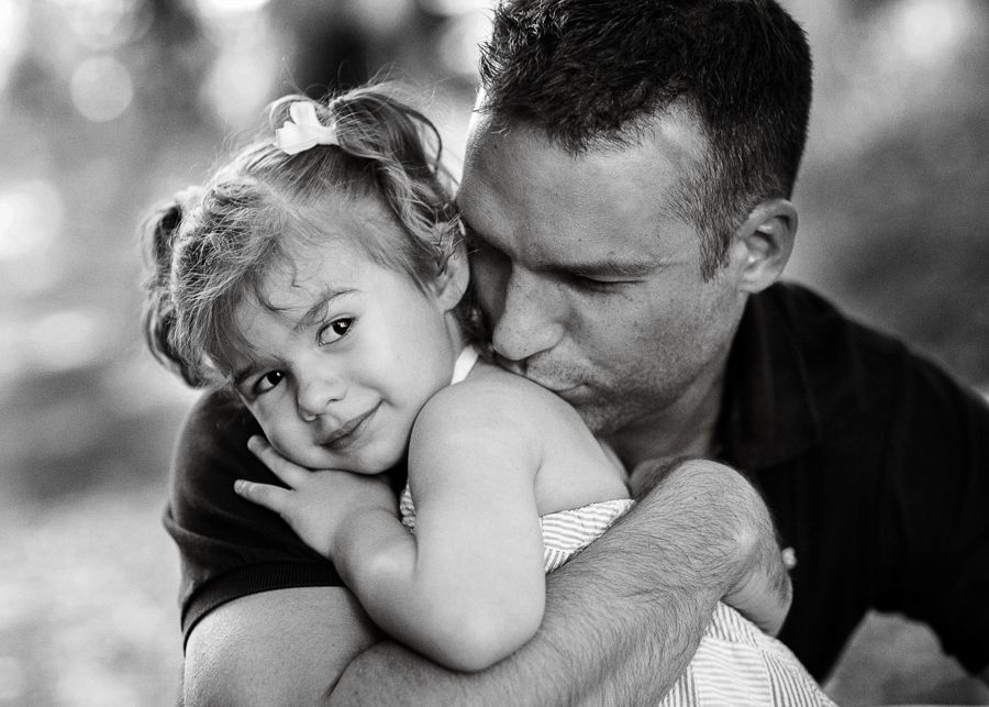 An intimate black and white portrait capturing a tender embrace between parent and child.