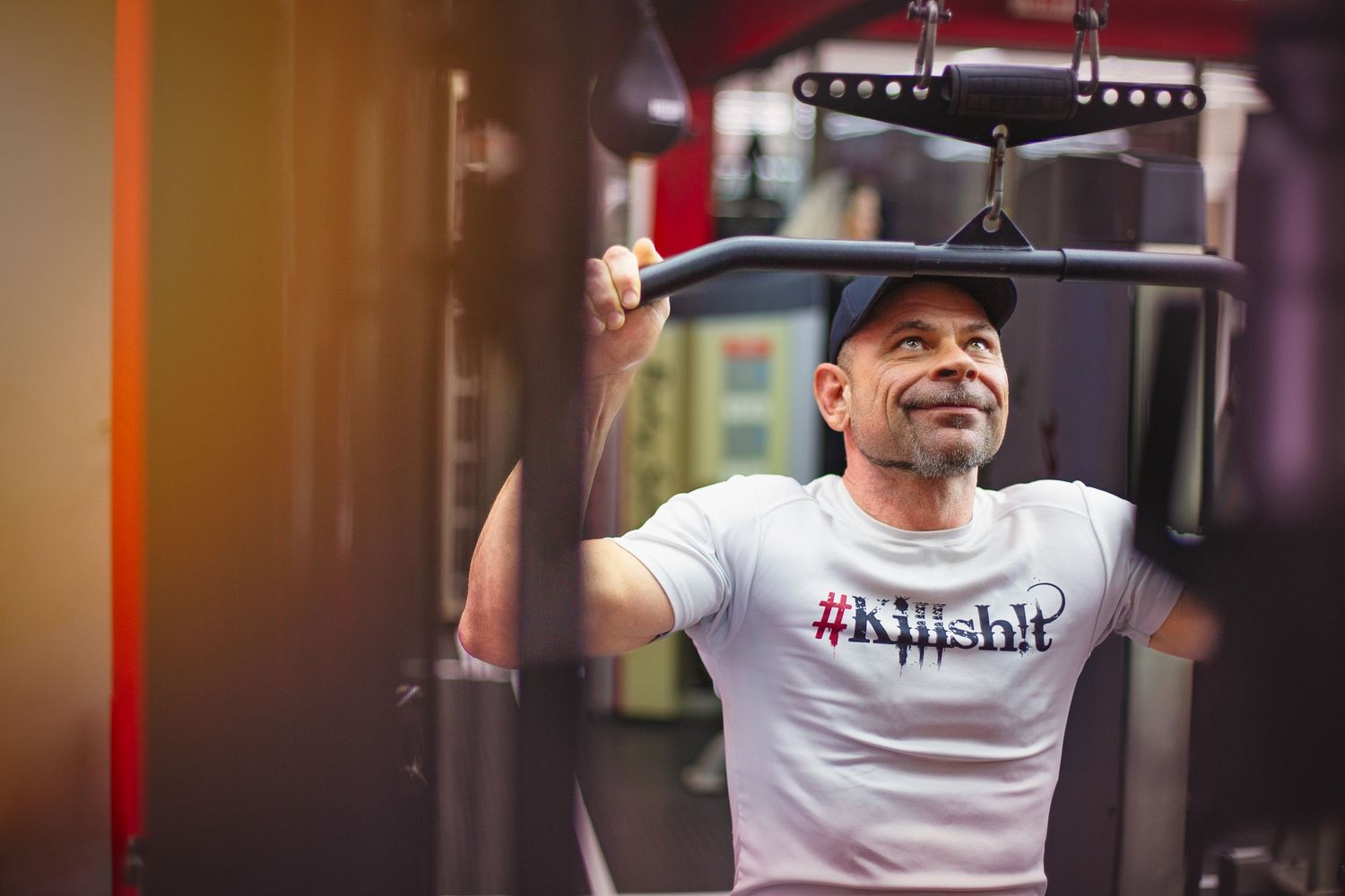 Person working out on exercise equipment wearing a hashtag t-shirt in a gym setting.
