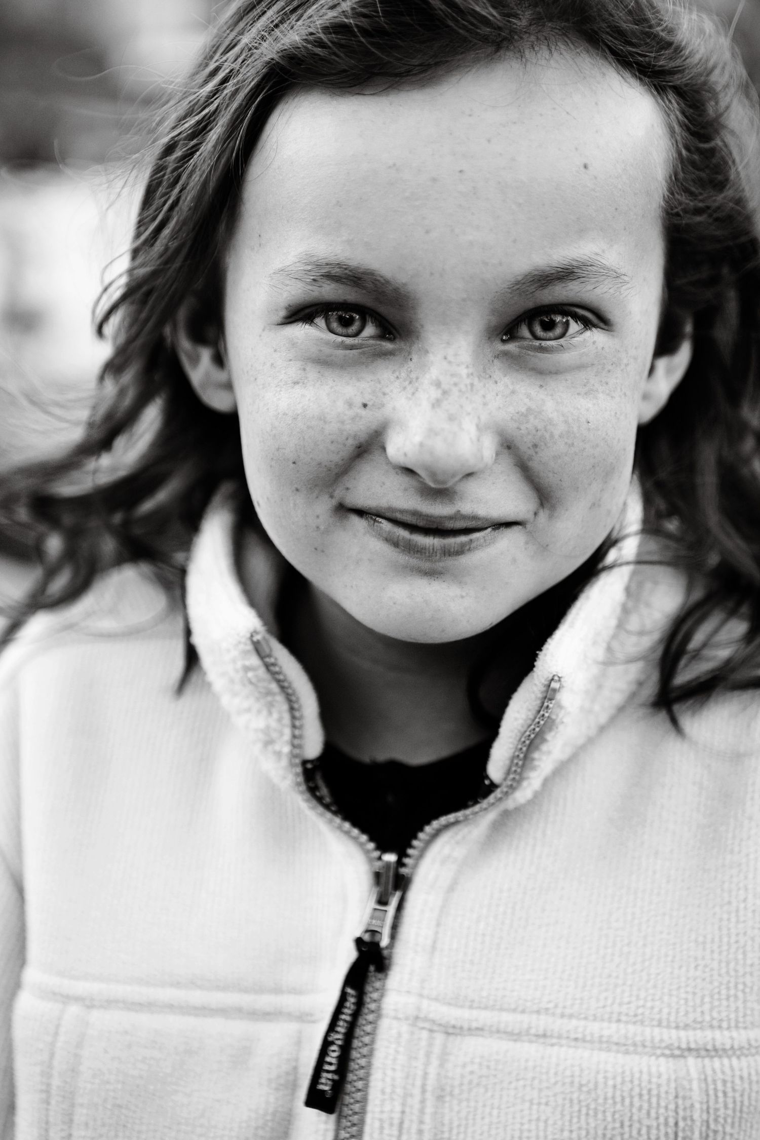 Black and white portrait showcasing freckles and natural beauty against soft lighting.