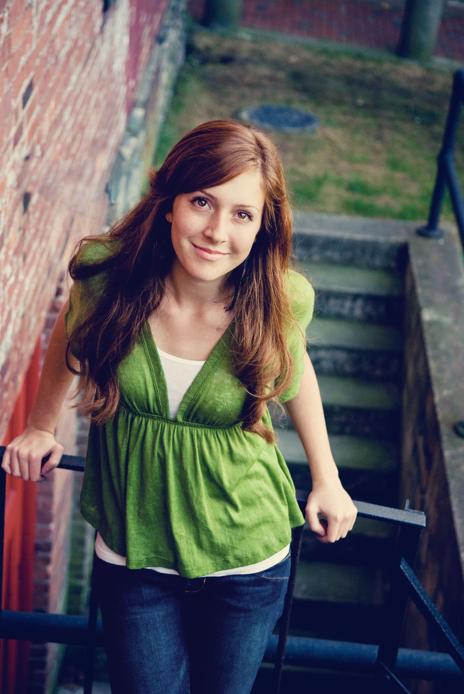 Portrait on rustic staircase wearing green empire-waist top.