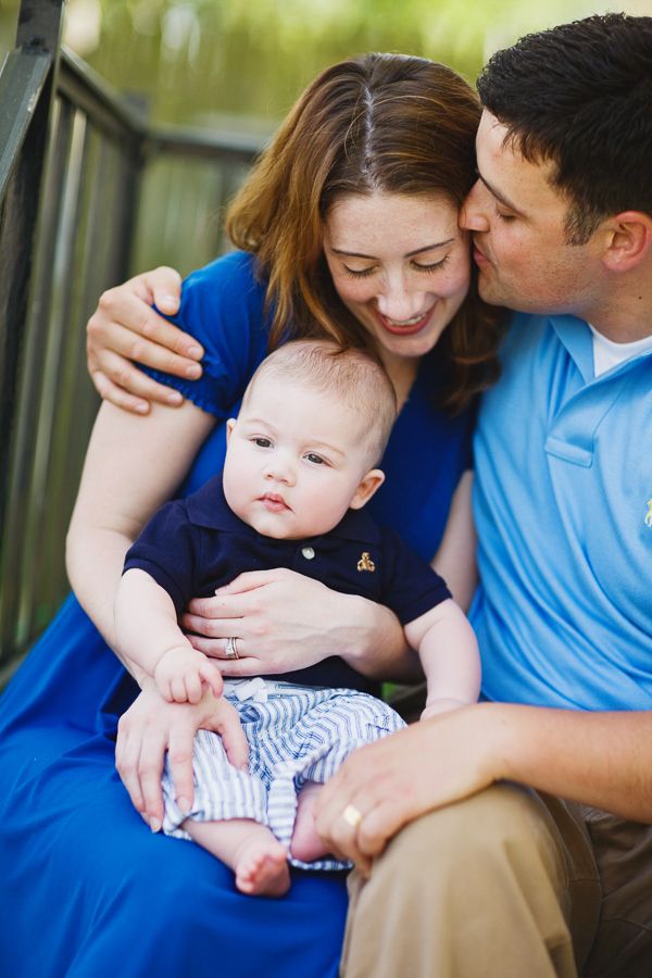 A family sharing an intimate moment outdoors on a bench in casual attire.